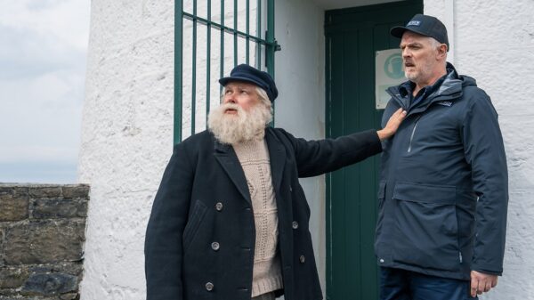 The Cleaner Series 3: Conleth Hill and Greg Davies stand at the entrance of a lighthouse. Conleth holds on to the jacket of Greg and looks at something in the distance.