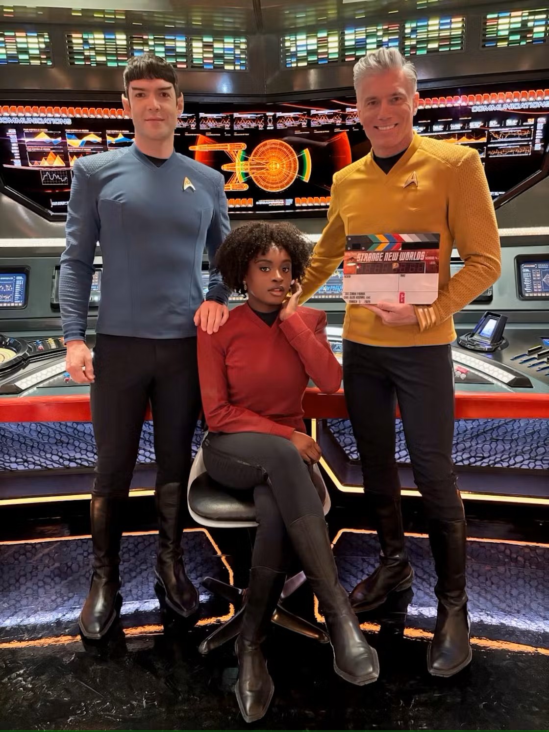 Star Trek: Strange New Worlds Season 4 - Ethan Peck, Celia Rose Gooding & Anson Mount (with chapperboard) on the Enterprise bridge set