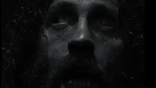 Terrified bedraggled man's face in black and white from the Werwulf trailer