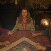 A still from The Witch Farm with characters conducting a seance